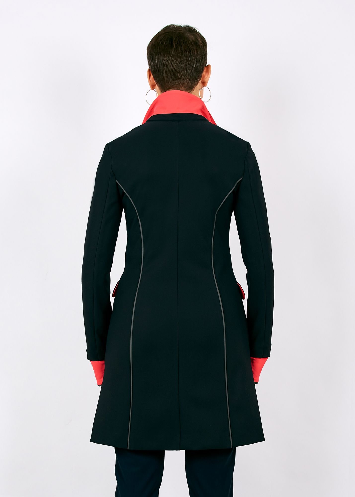 manteau de dos, noir, col relevé, envers de col et manchons corail, 2 passepoils rétroréfléchissants verticaux soulignent discrètement la ligne, n'étant pas éclairés